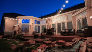 A house sits late in the evening with a set of permanent Christmas lights glowing under the soffit.