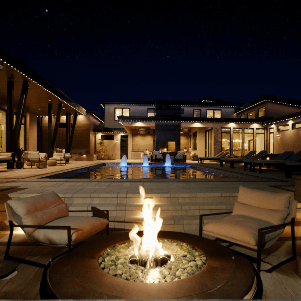 A cozy fire sits against the backdrop of a home lit with ambient lighting from permanent Christmas lights.